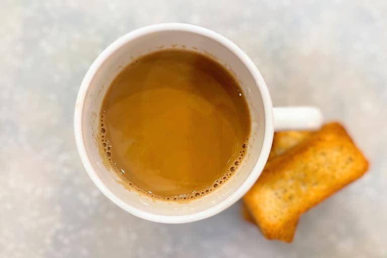 A cup of chai tea with biscotti.